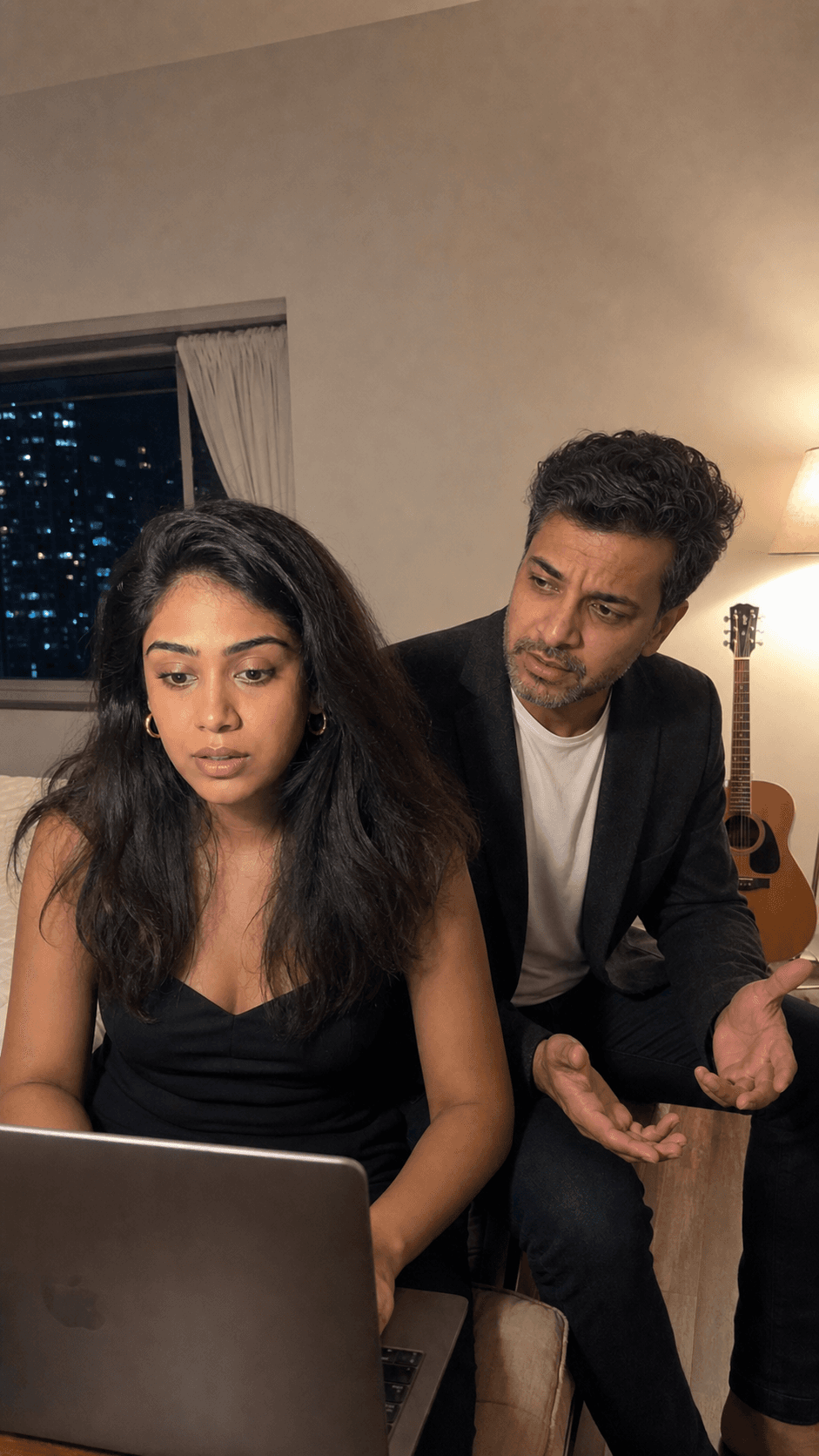 A woman focused on her laptop while her husband tries to talk to her